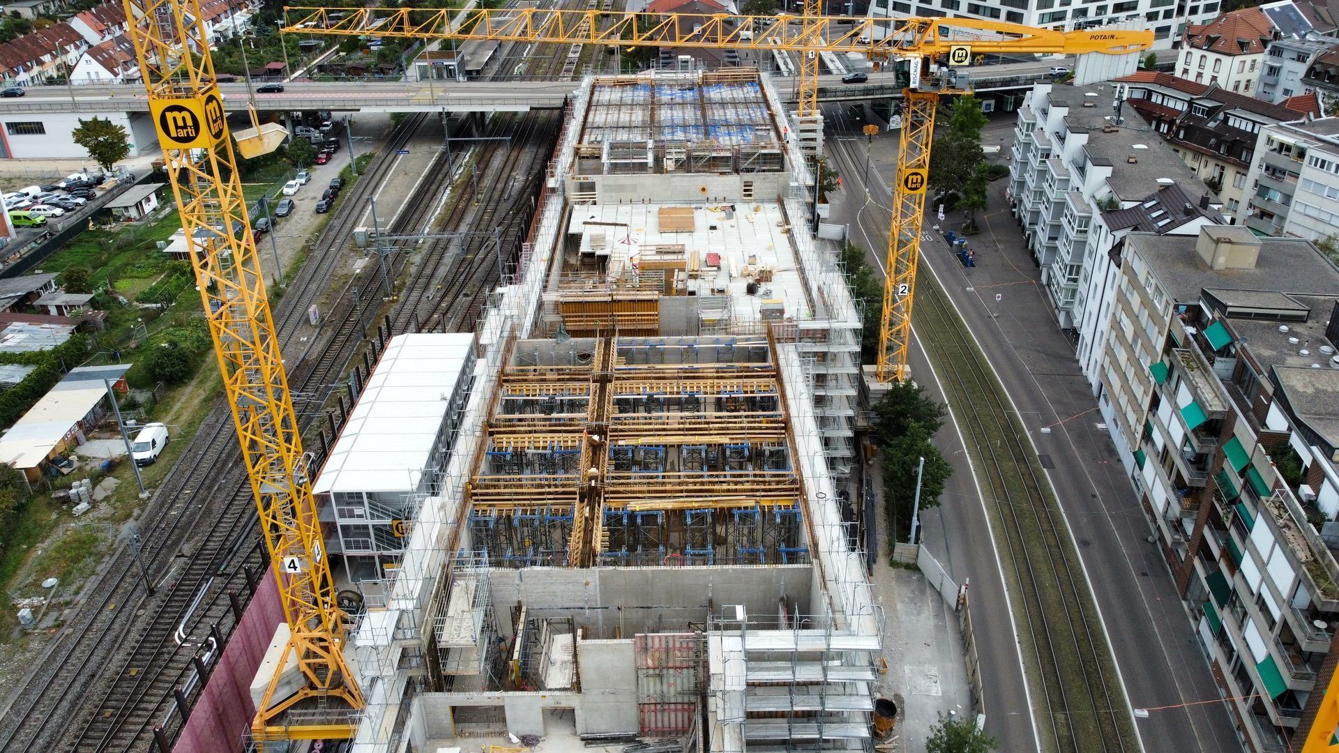 Baustelle an einer Bahnlinie von oben mit Kran und Bewehrung